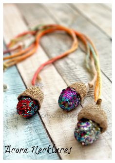 three necklaces with different colored beads and string on wooden table next to orange cord