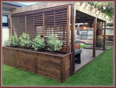 a wooden deck with plants on it and a grill in the back ground next to it