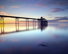 a long pier sitting on top of a large body of water under a cloudy sky