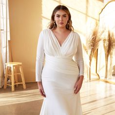 a woman in a white wedding dress posing for a photo with her hands on her hips