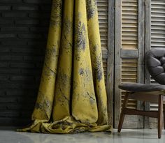 a chair sitting next to a window covered in yellow curtains