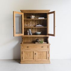 a wooden hutch with glass doors on the front and shelves above it, in a room