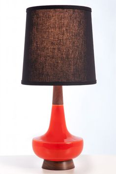 an orange table lamp with a black shade on the base and a brown lampshade