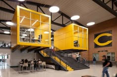 the inside of a building with stairs and people sitting at tables in front of it