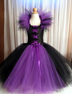 a purple and black dress on display in front of a white curtain with the word rainbow boutique's post