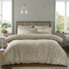 a bed with white comforter and pillows in a room next to two lamps on the wall