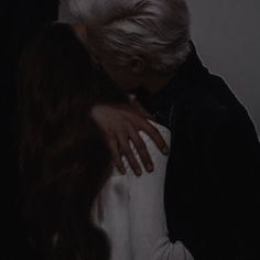 an older woman with white hair is hugging her younger lady's shoulder in the dark