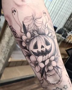 a black and white photo of a person with a pumpkin tattoo on their arm,