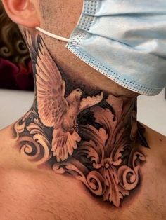 a man with a neck tattoo has an eagle on his chest and is wearing a surgical mask