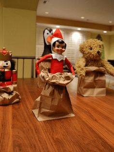 an elf is sitting in a paper bag next to two stuffed animals on the table