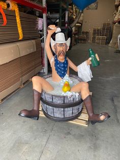 a statue of a man sitting in a barrel with a hat and bandana on