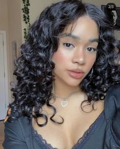 a close up of a person with curly hair wearing a bra and necklace in front of a mirror