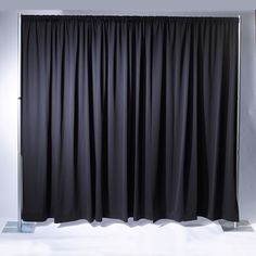 a black curtain hanging on the side of a white wall