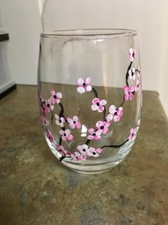 a clear glass with pink flowers painted on the side and black stems in the middle