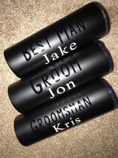 three black cans with the names of grooms and best man on them sitting on carpet