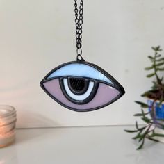 a glass eye hanging from a chain next to a potted plant and candle holder