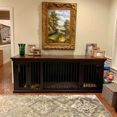 a painting is hanging on the wall above a dog kennel in a living room