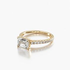 a gold engagement ring with a baguette cut diamond in the center and side stones