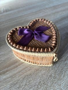 a heart shaped box with a purple bow on it's lid sitting on a table