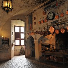 an old kitchen with pots and pans hanging on the wall