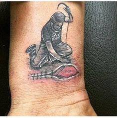 a tattoo on the wrist of a man with an image of a baseball player holding a bat