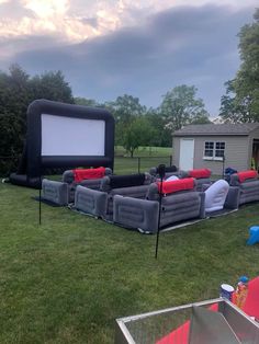 an inflatable movie screen is set up on the lawn with red and white pillows