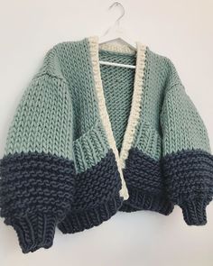 a green and blue sweater hanging on a hanger