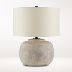 a table lamp with a white shade on the base and a light bulb in front of it