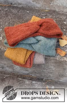 four knitted hats sitting on top of each other in front of a stone wall