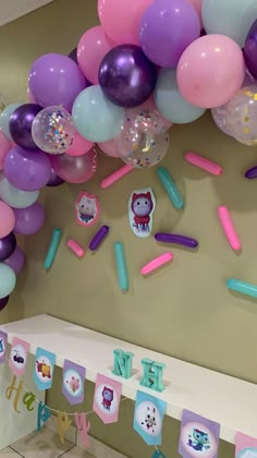 balloons and streamers are hanging from the ceiling in front of a birthday party banner