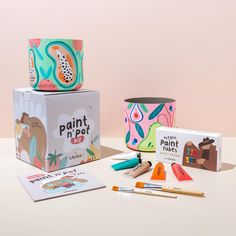 the paint pot is next to its box and other crafting supplies, including scissors