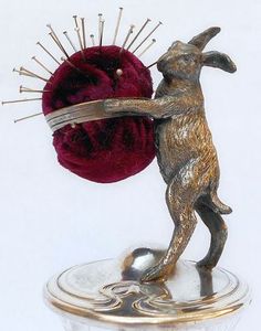 a metal dog figurine holding a ball of thread