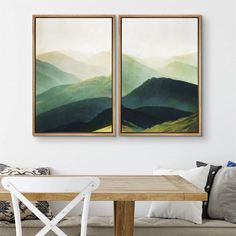 two paintings hanging on the wall above a table