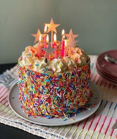 a birthday cake with lit candles and sprinkles on it sitting on a plate