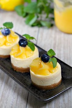 three small desserts on a black plate with blueberries