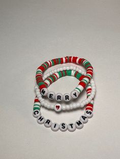 "Merry Christmas Clay Bead Bracelet set of 3.  One says \"Merry\", One says \"Christmas\" and one is white seed beads with single heart.  This is a set of 3 bracelets.  Stretchy, one size fits most." Christmas Beaded Bracelets Ideas, Clay Beads Christmas Ideas, Christmas Bracelets Clay Beads, Preppy Clay Bead Bracelets Christmas, Clay Beads Bracelet Ideas Christmas, Cute Bracelet Ideas Glass Beads, Clay Beads Christmas, Christmas Clay Bead Ideas, Winter Clay Bead Bracelet Ideas