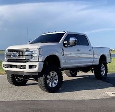 a white pickup truck parked on the side of a road near a body of water