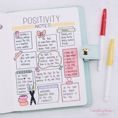 an open notebook with writing on it next to two markers and a pen, which is also labeled positivity notes