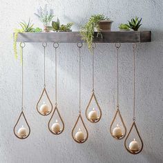 a shelf with hanging candles and plants on it