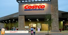 people walking in front of a costco store at dusk with lights on the building