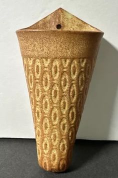 a brown vase sitting on top of a black table next to a white wall and floor