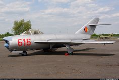 a fighter jet sitting on top of an airport tarmac with trees in the background