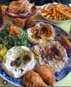 a blue and white plate topped with different types of food next to other plates of food