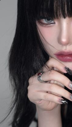 a woman with long black hair and silver nails