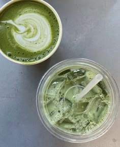 two cups filled with green liquid next to each other on top of a gray table