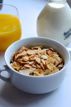 a white bowl filled with cereal next to a glass of orange juice