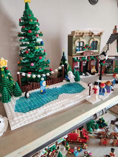 there is a lego christmas tree on the shelf in front of other toys and buildings