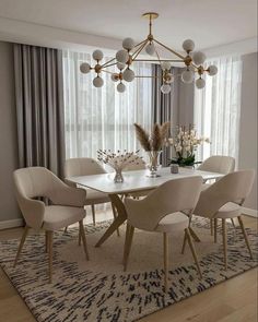 a dining room table with white chairs and a chandelier hanging from the ceiling