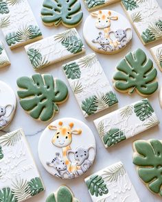 decorated cookies with green leaves and giraffes are on a white tablecloth