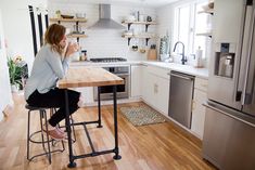 a woman sitting at a kitchen table drinking coffee